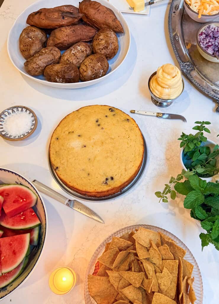Baked potatoes, cornbread, whipped butter, and watermelon for a rodeo dinner party.