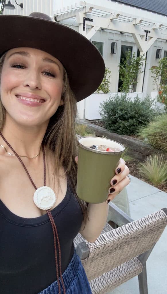 Eden Passante drinking ranch water out of an enamel green cup.