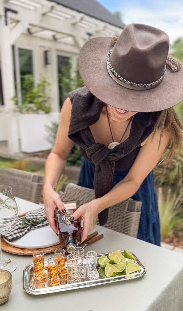 Eden Passante pouring tequila in a small glass cowboy boot shot glass.