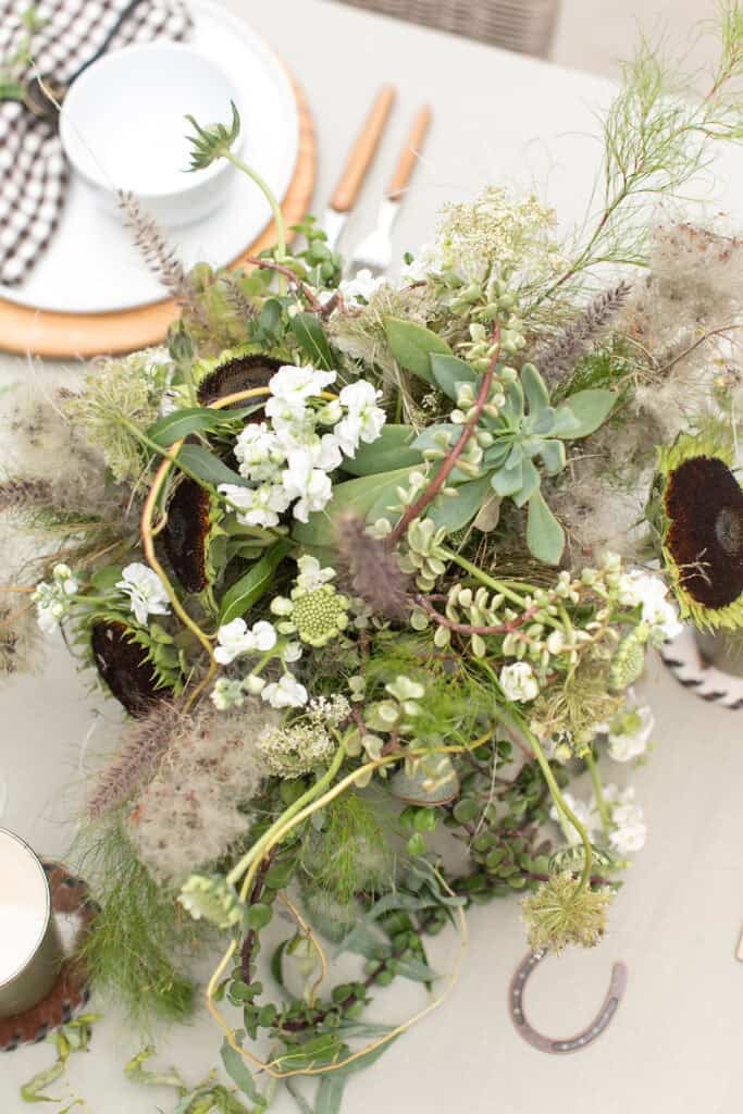 Flower arrangement filled with green and white flowers, succulents, and sunflowers.